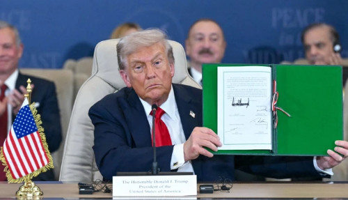 Trump holds up the document with his signature, and looks very grumpy