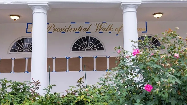 The words 'Presidential Walk of Fame, in
a giant, script font are stenciled on the wall in gold, and there are 20-30 frames wrapped in brown paper, either waiting to 
be filled, or waiting to be revealed