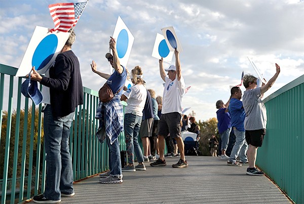People holding blue dot signs