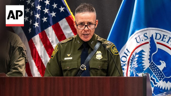 Greg Bovino in a military 
uniform, wearing a belt that also has a strap that goes across his chest.