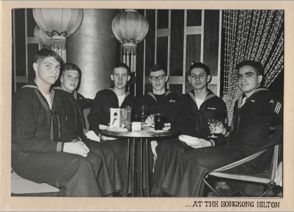 A black-and-white
photo of six sailors wearing regular Navy blues, sitting around a table at the Hong Kong Hilton sharing drinks.