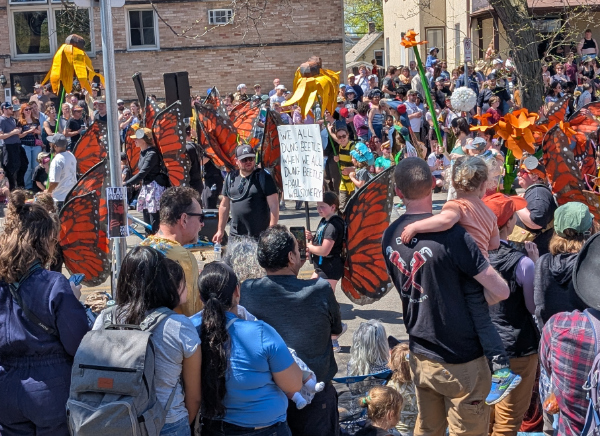 A very robust parade,
with most marchers wearing butterfly wings. In the center is someone holding a poster that says 'We all dung beetle when we all dung beetle.'