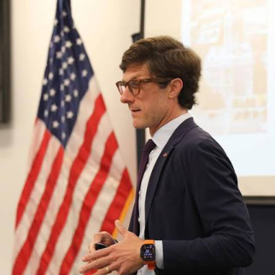 White guy, square jaw, wavy
brown haircut, horn-rimmed glasses