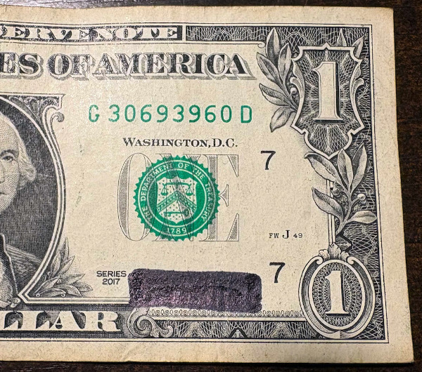 A $1 bill with the signature blacked out
