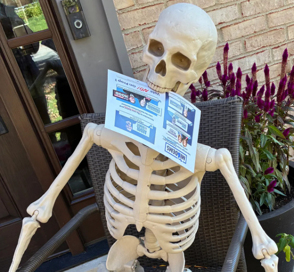 A Halloween skeleton with a political flier in its mouth