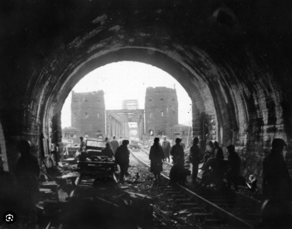 A black and white
photo of a large tunnel; you can see perhaps a dozen people and a bunch of wreckage caused by bombing